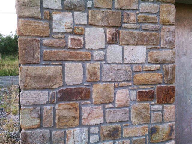 A wall of natural rectangular stones in tan, brown and grey