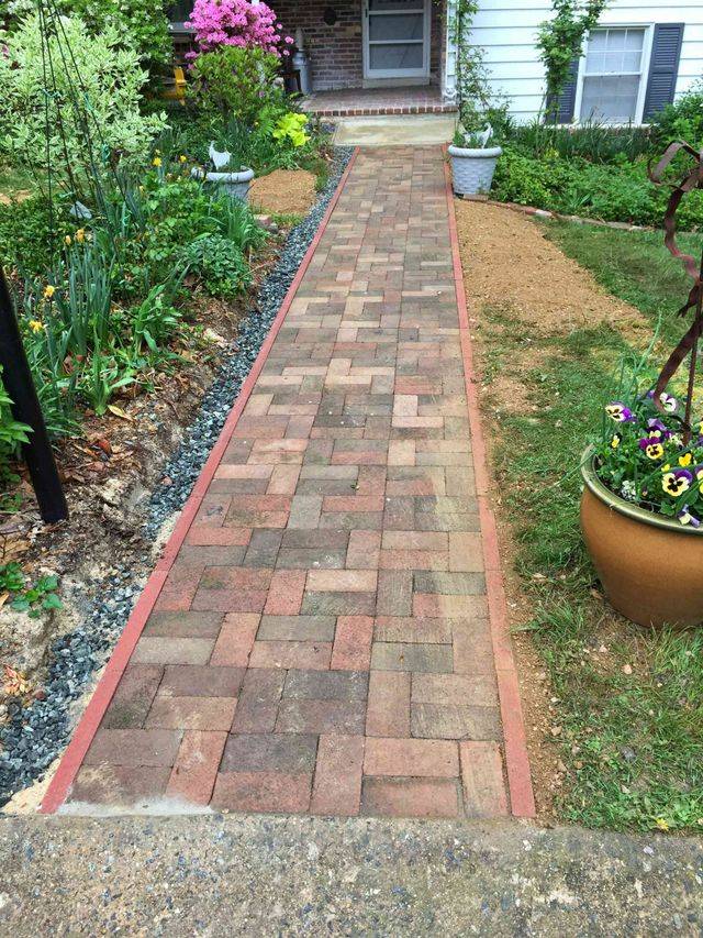 A brick walkway with a red border leading to a front door